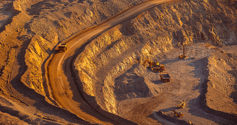 Aerial view of a large open pit, revealing its expansive, rugged terrain and surrounding landscape.