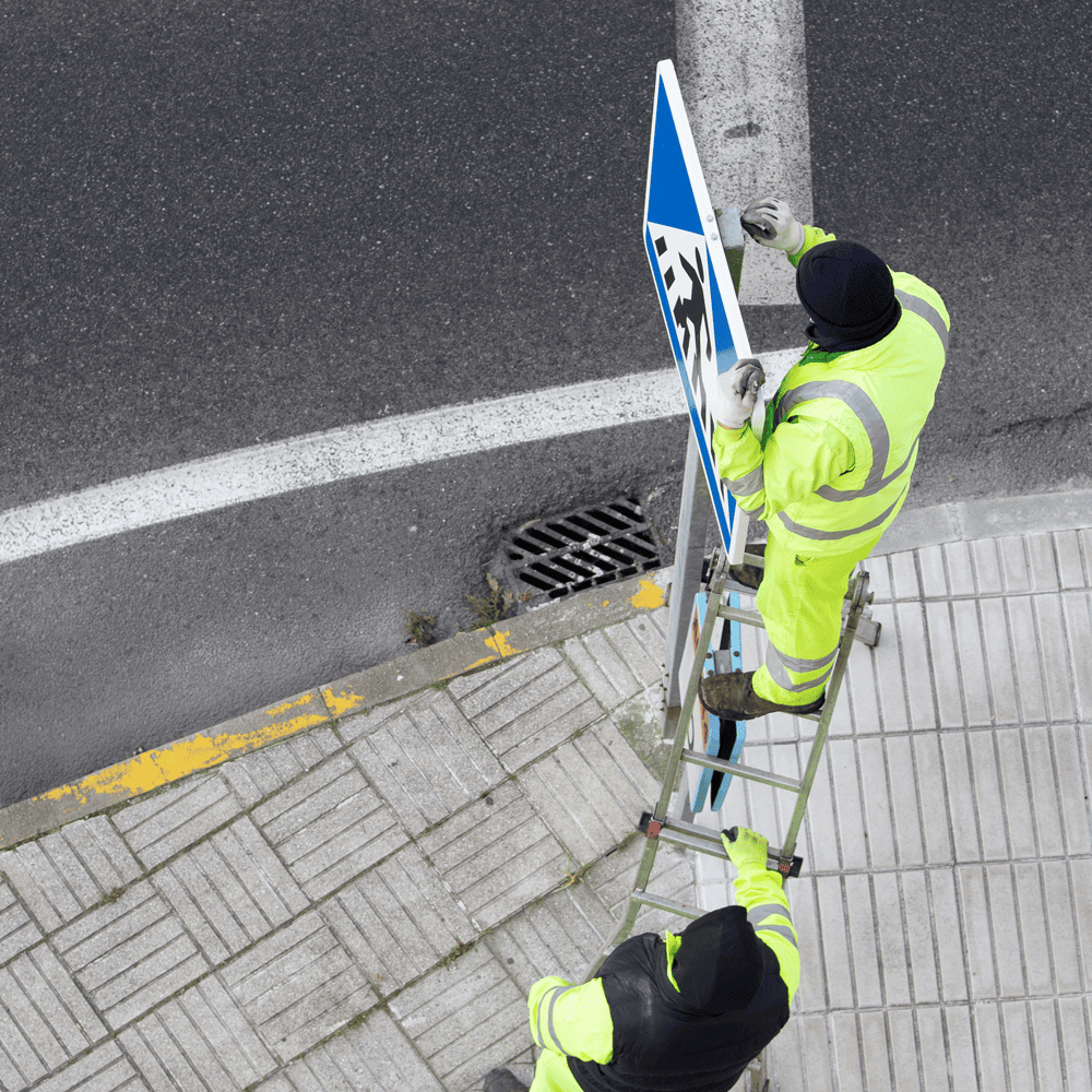 Checking Quality Signs - Men installing a sign on a street
